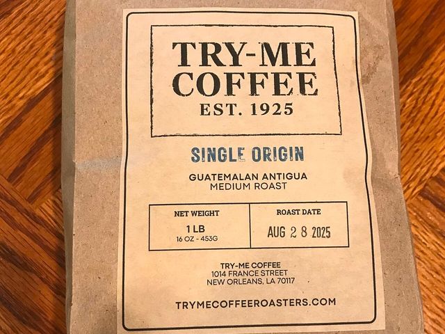 A kraft paper coffee pouch with a printed label, lying on a wooden table