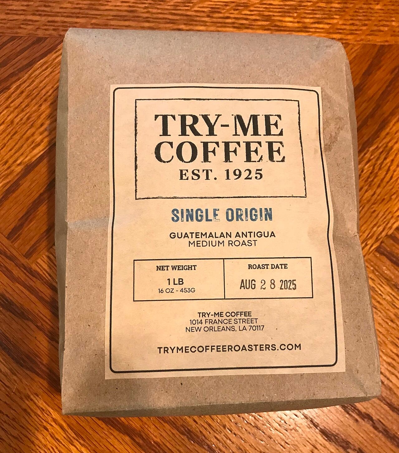 A kraft paper coffee pouch with a printed label, lying on a wooden table