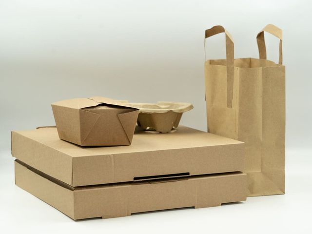 Brown board boxes, a food box and a paper carrier bag on a pale background