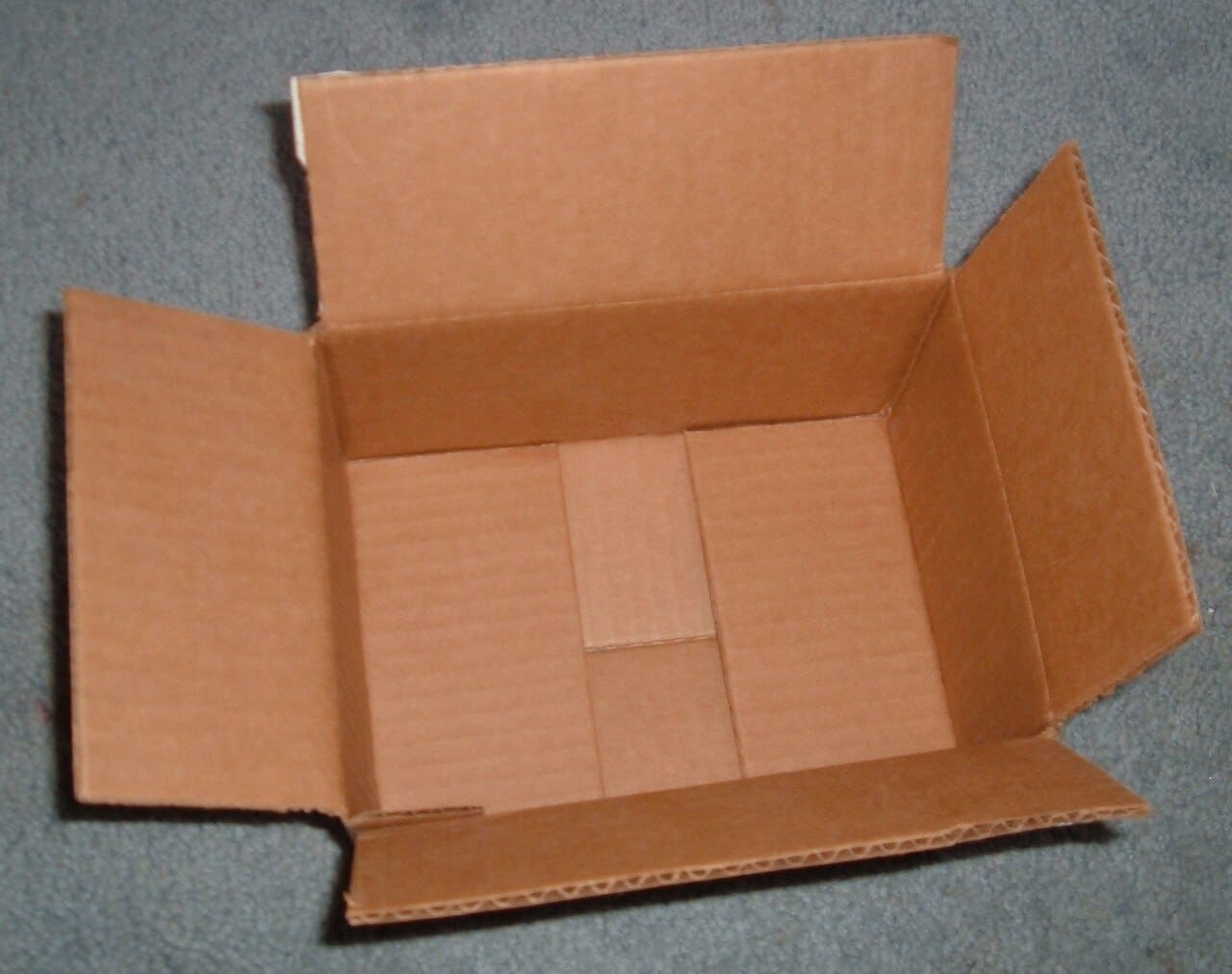 An open brown corrugated box seen from above, flaps folded out