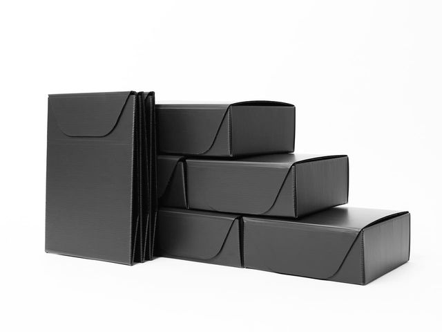 Black reusable shipping packs, folded flat and stacked, on white