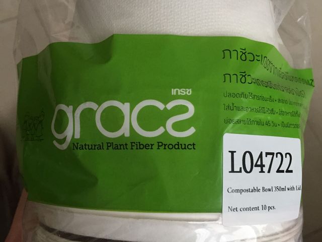 A sleeve of white sugarcane fibre bowls held in a hand