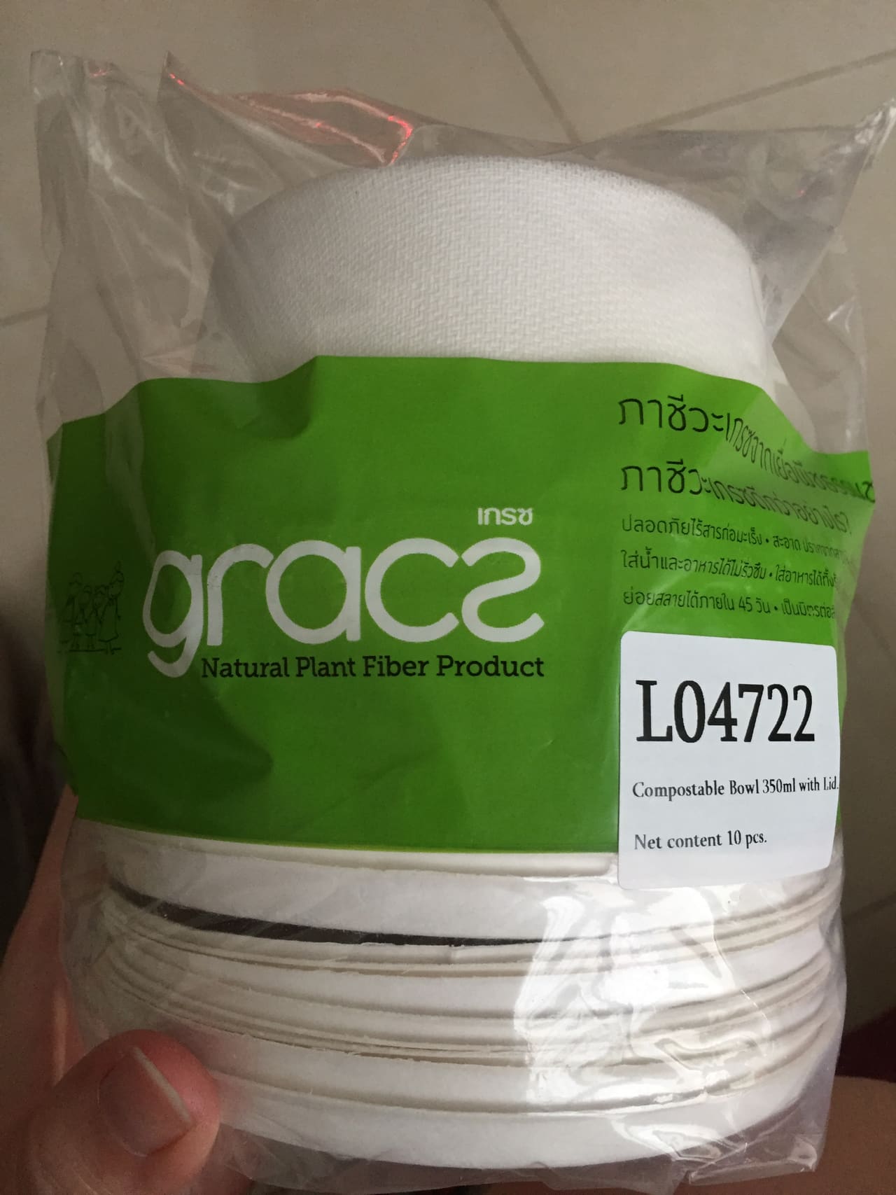 A sleeve of white sugarcane fibre bowls held in a hand