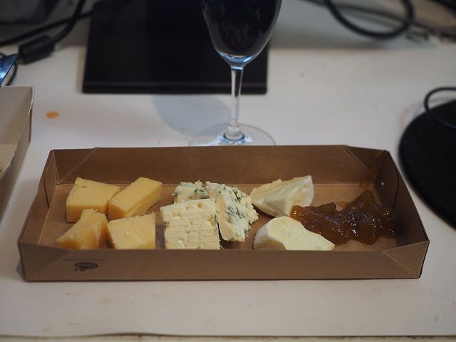 A shallow folded board tray holding pieces of cheese